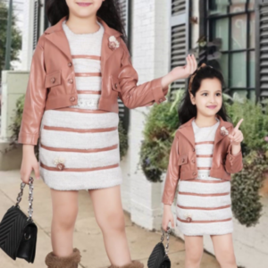 A young girl wearing a black faux leather biker jacket over a black and white striped fuzzy knit dress, styled with matching fur-trimmed boots and a mini handbag.